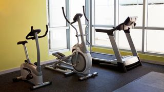 A workout bike, elliptical machine, and treadmill sitting next to each other in a gym, representing the 15-15-15 workout