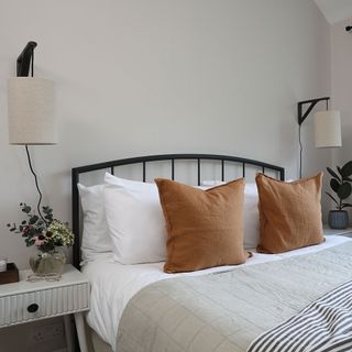 Bedroom with metal-framed bed, wall lights and white bedside table