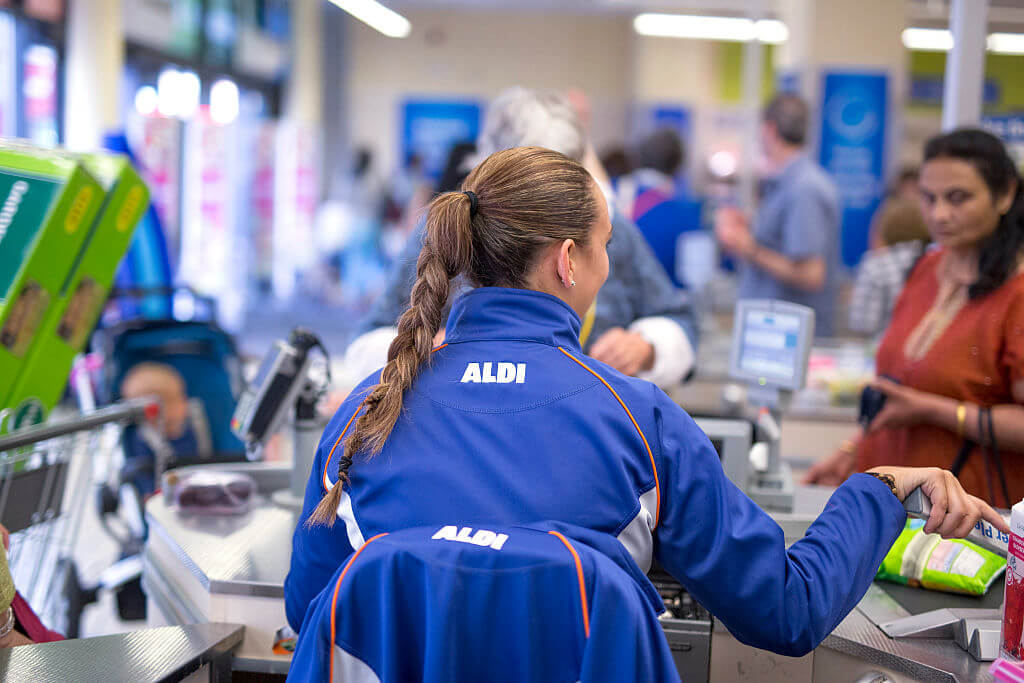 A member of staff prepares to scan goods taken from a customer's shopping basket at the check-out counter inside an Aldi supermarket store in London,