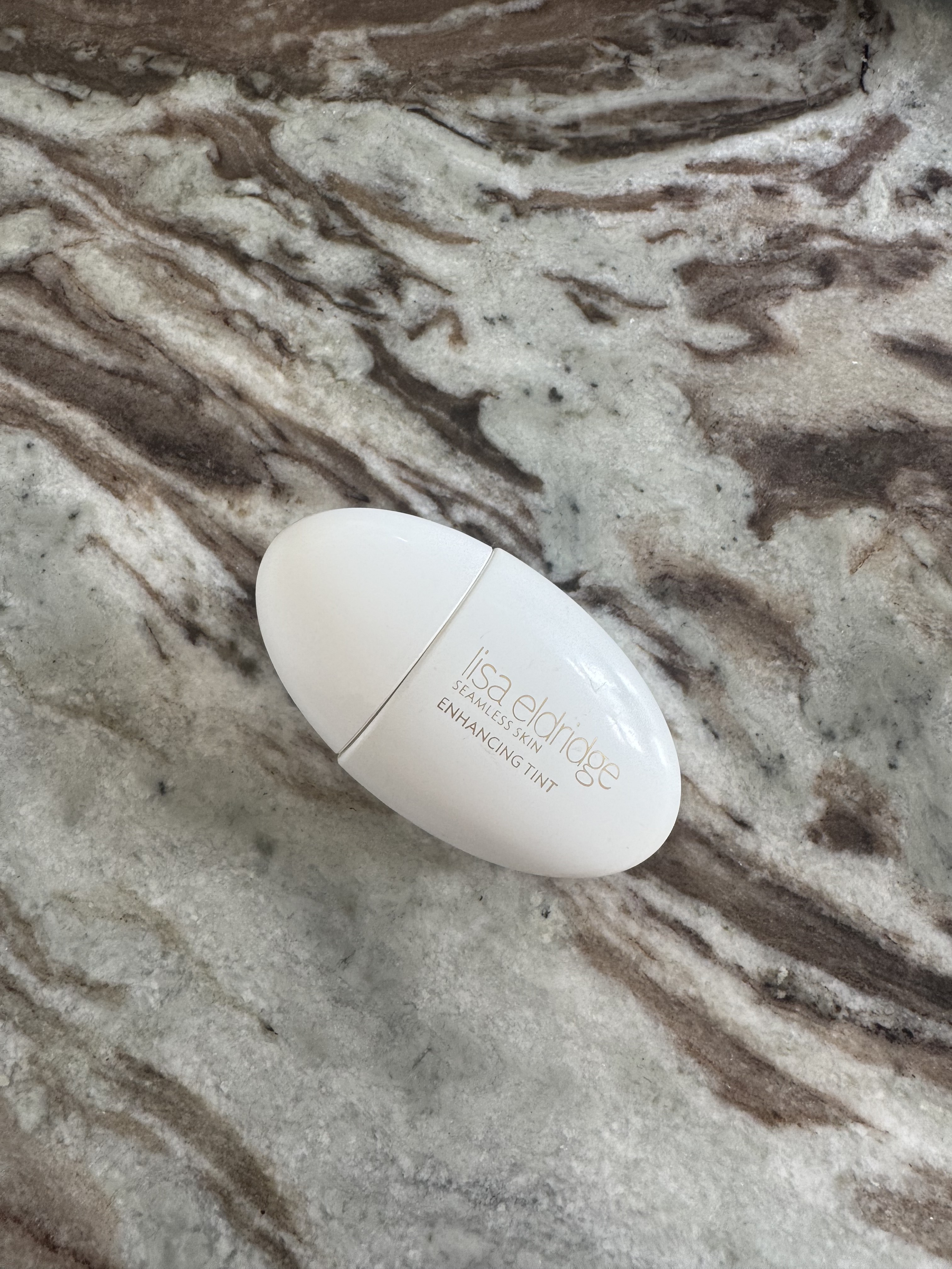 A photo of the Lisa Eldridge Seamless Skin Enhancing Tint on a marble table