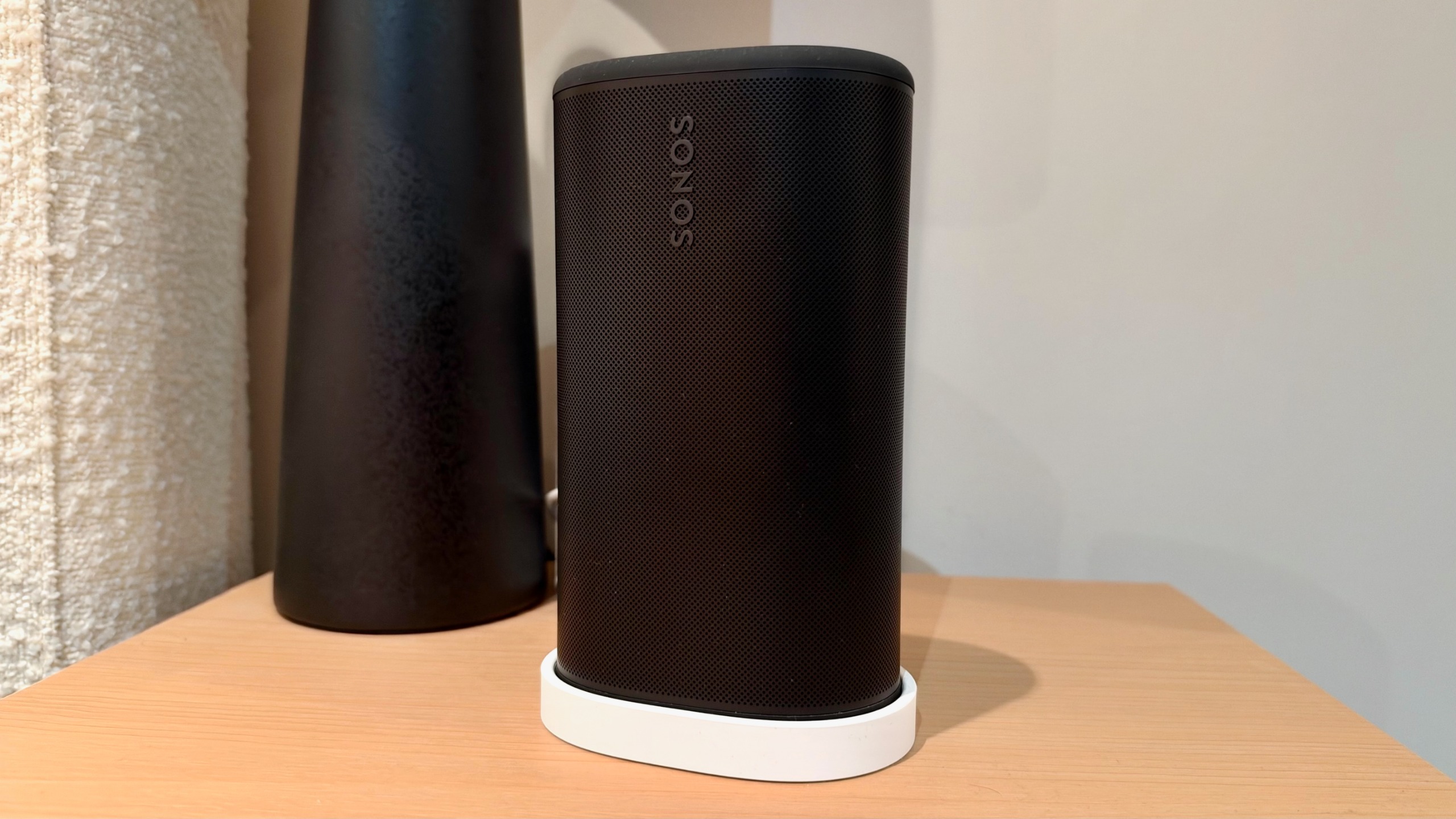 Black Sonos Play speaker on a bedside table.