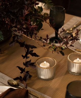 dining table with pair of white candles in glass pots with gold rim