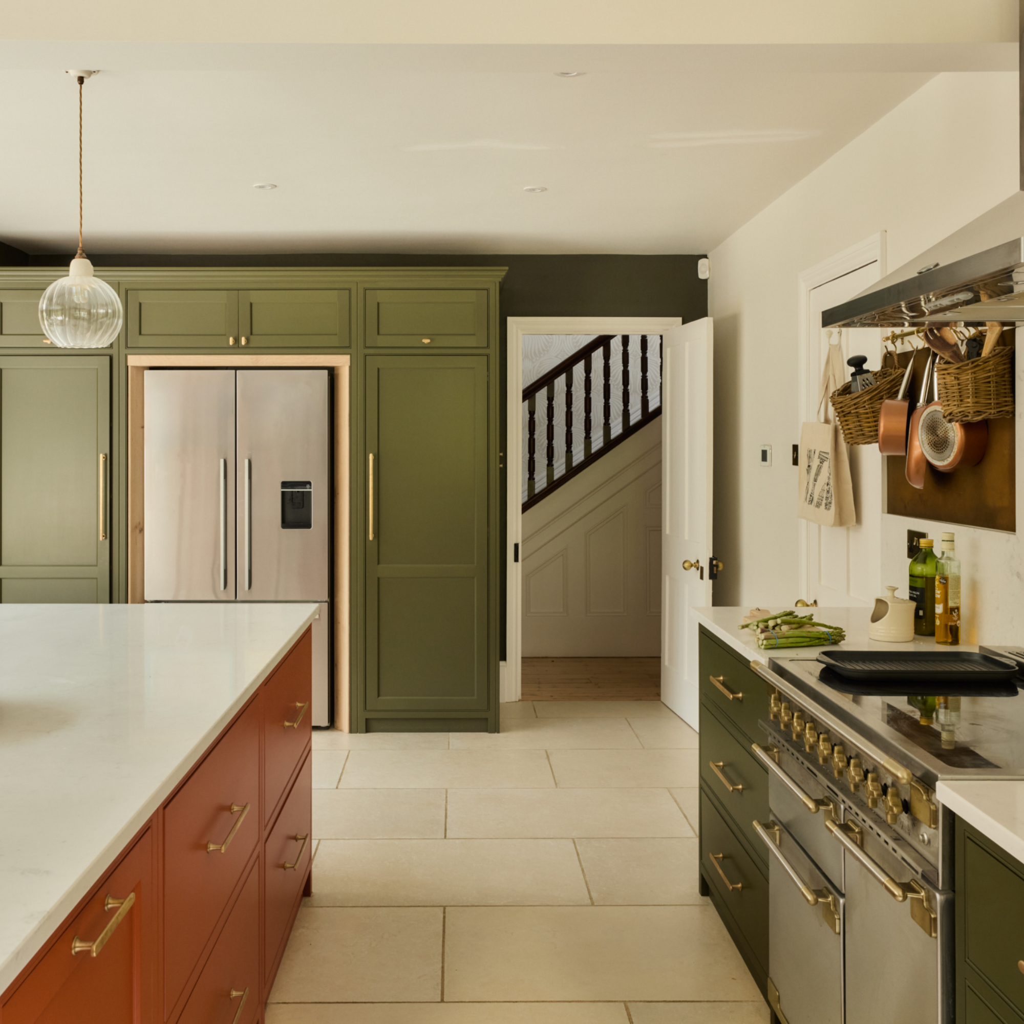 green and terracotta kitchen with white worktops and off white floor tiles, integrated fridge, floor to ceiling storage