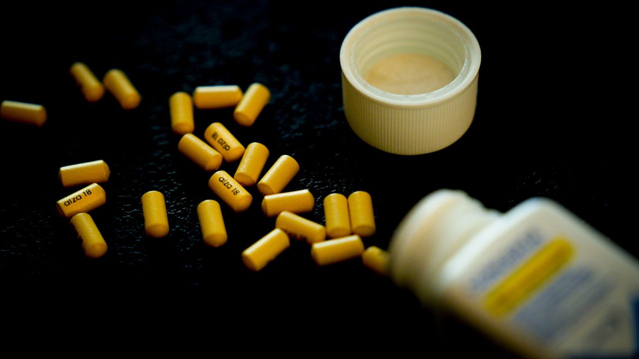 Pills for ADHD spilling out of an open medicine bottle