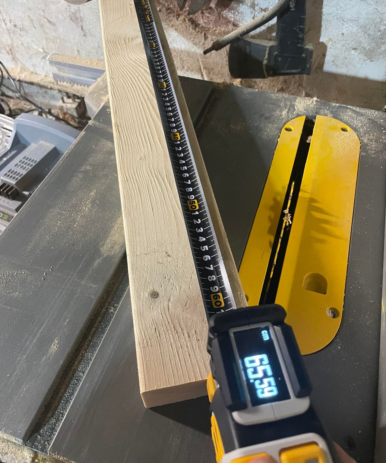 A digital tape measure measuring the length of a plank of wood