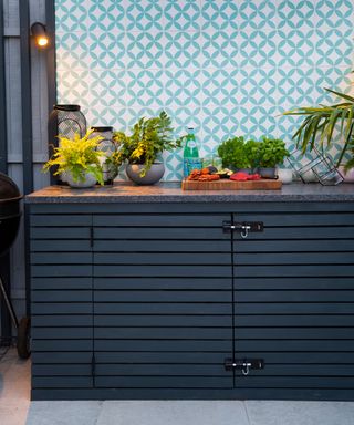 A midnight blue painted outdoor kitchen unit with pale blue and white tiles.