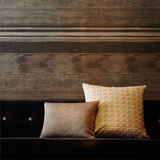 2 cushions on a brown wooden bench in front of wooden wall