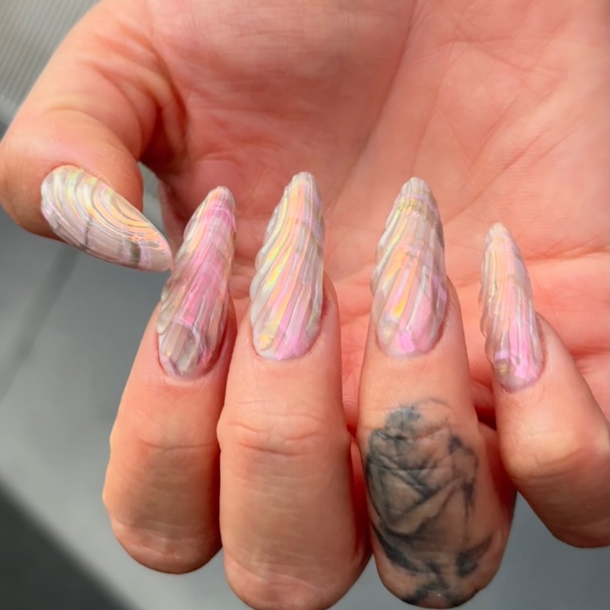 Long stiletto nails sculpted with raised oyster shell ridges in pink and yellow iridescent tones