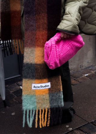 A close up of an Acne Studios scarve and neon pink bag