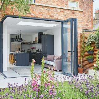 Exterior of house showing corner bifold doors leading out onto garden with lavender plants