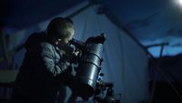 A child using one of the best telescopes for kids outside while camping