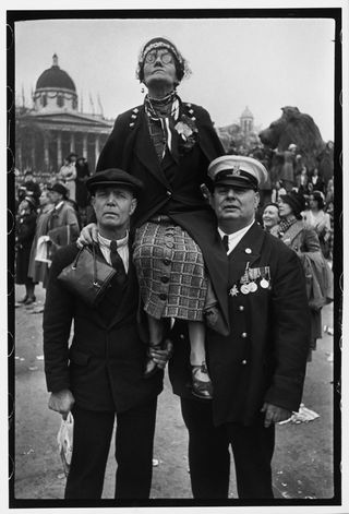 Black and white photo -Old lady on two mens shoulders at the Coronation of King George VI, Trafalgar Square, London