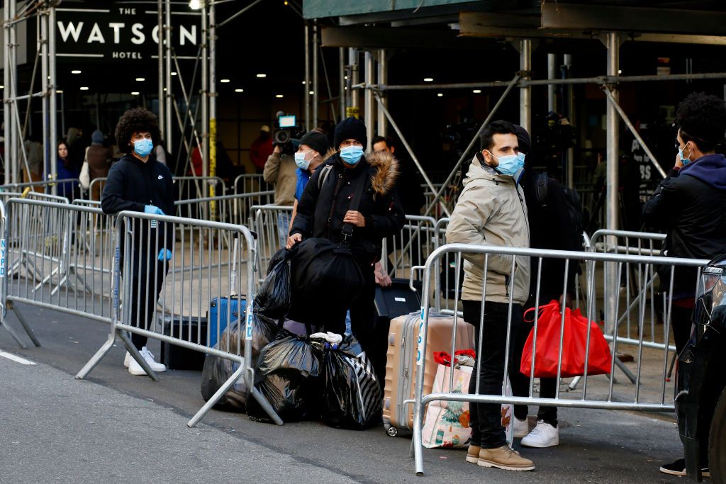 Migrants wait for a bus in front of the Watson Hotel in New York City