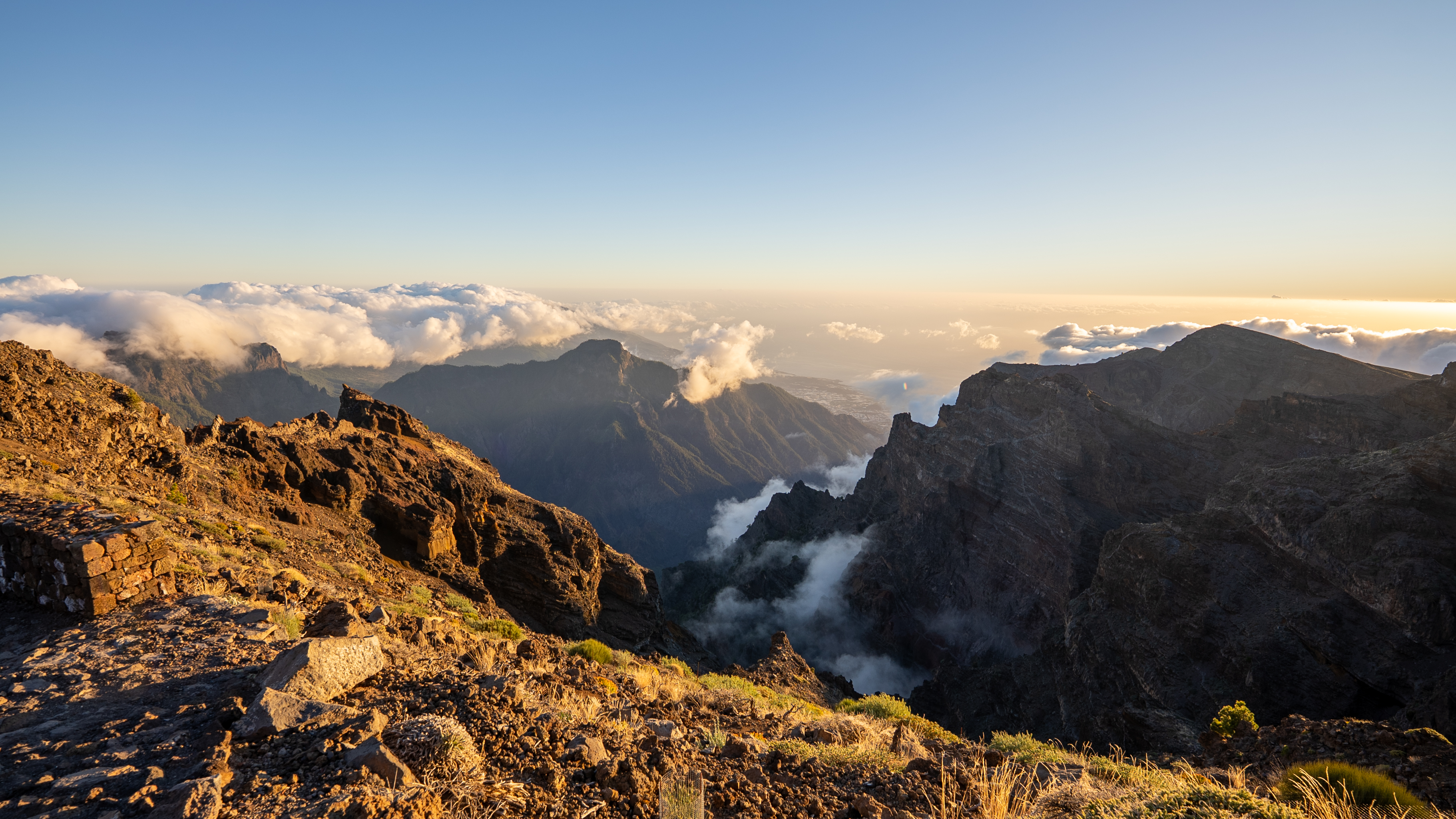 golden colored landscape as the rocks shine in the last of the daylight with blue skies above and clouds below