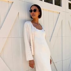 A woman in a white dress and cardigan with a short, polished bob hairstyle