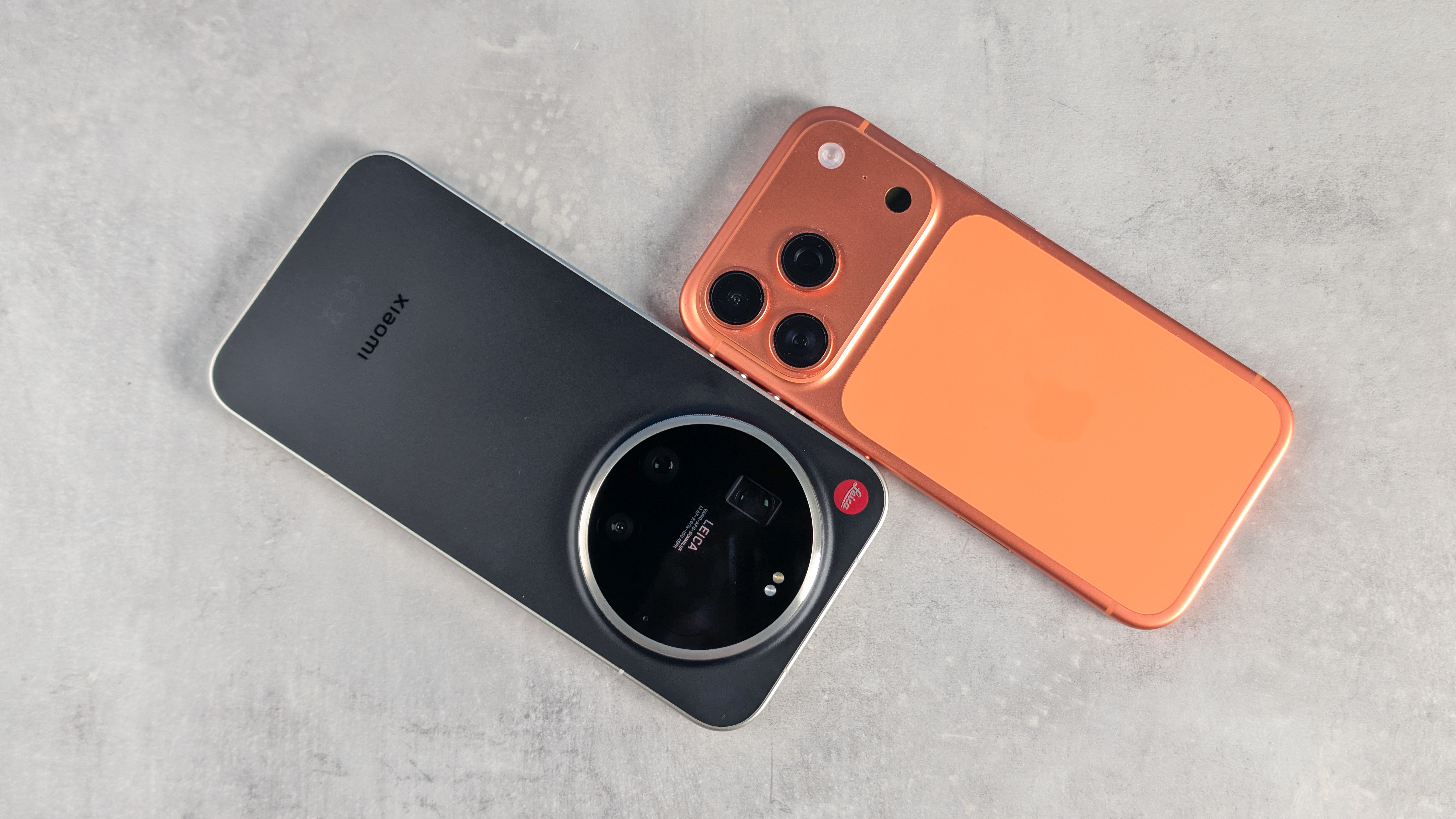 A black Leica Leitzphone and an orange iPhone 17 Pro