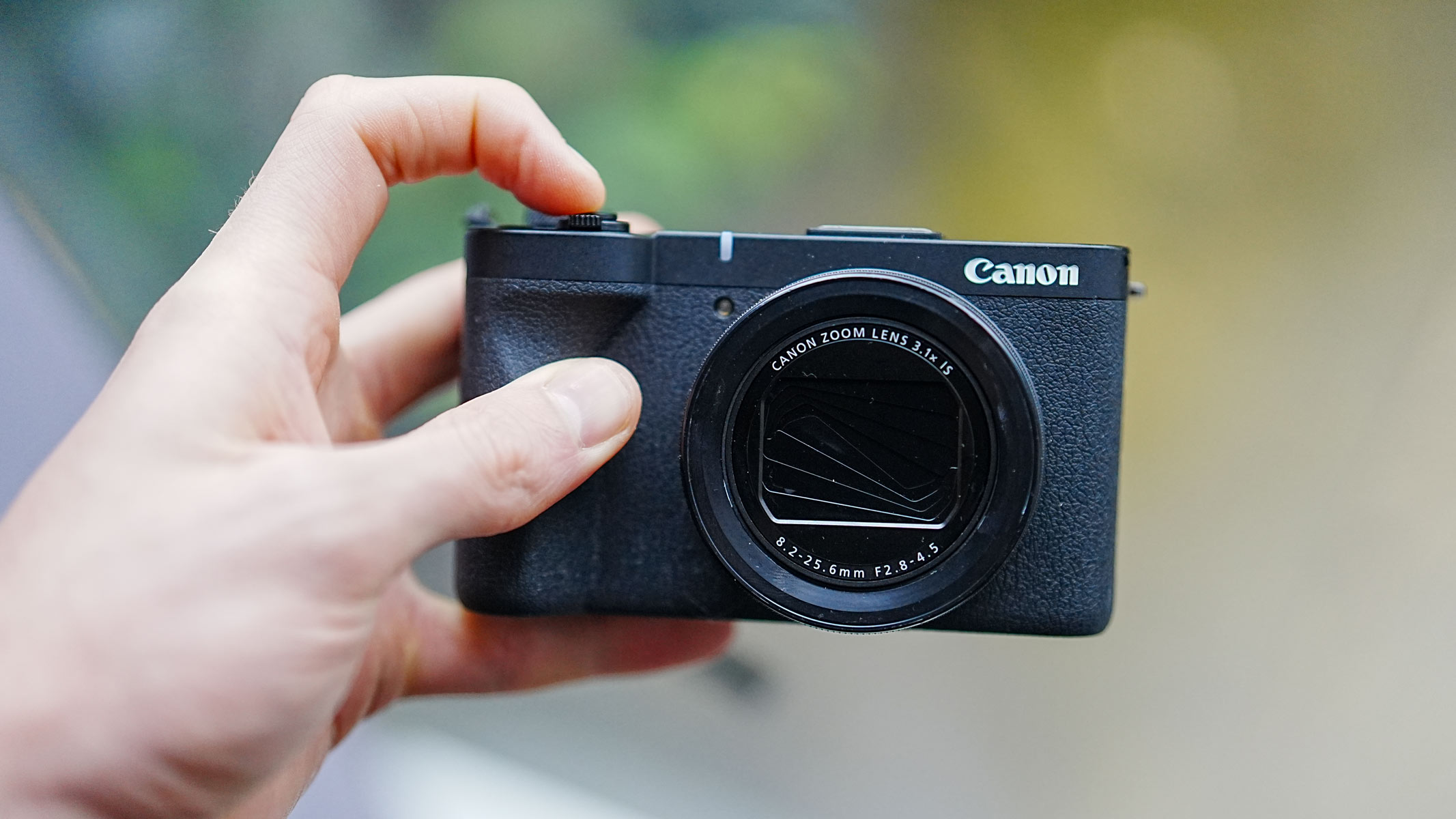 The Canon Powershot V1 being held in a hand with the shutter closed and facing the camera.