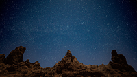 interesting rock formations with jagged peaks and a starry sky above.