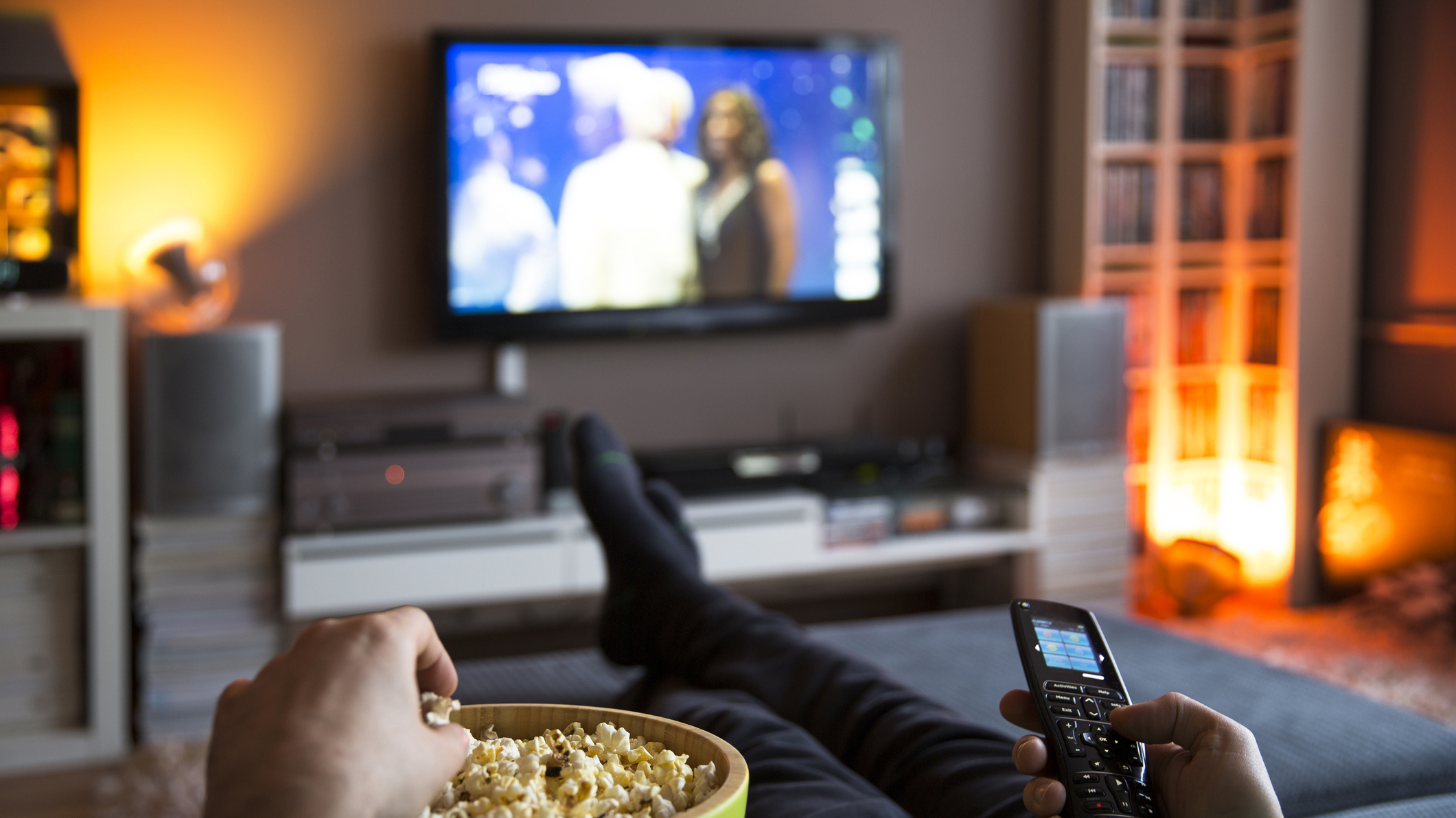 Man relaxing at home watching TV and eating popcorn