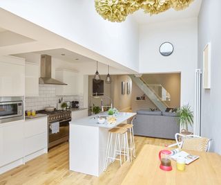 open plan kitchen, diner living room painted white with white gloss kitchen, feature grey wall, grey sofas