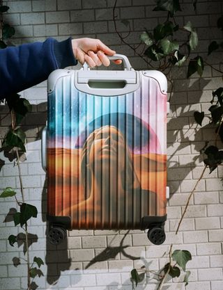 Person holding Rimowa x Palace suitcase with airbrushed print