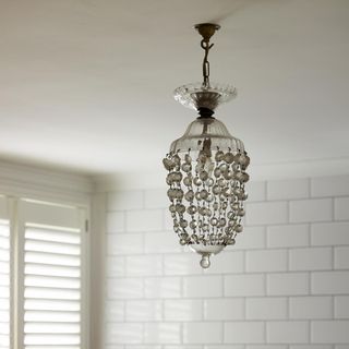 bathroom with white tiles on wall and chandelier