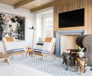 Small cozy living room with white and grey armchairs around fireplace