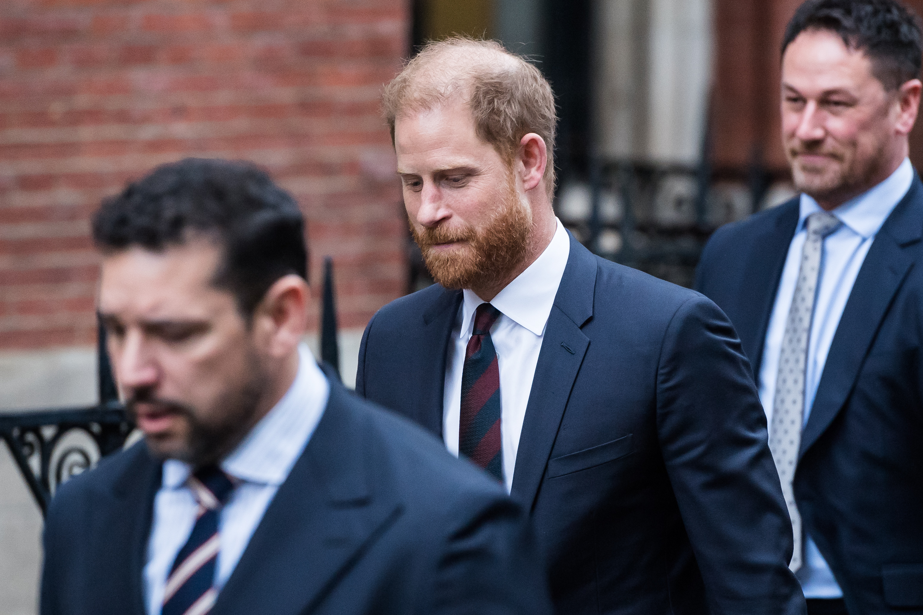 Prince Harry walking outside court in a blue suit