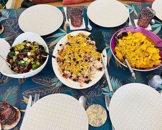 A dining table with dishes of Persian food including cherry saffron rice, saffron chicken and salad