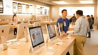 A young Apple sales assistant talks to a customer next to iMacs in the Apple store interior shop in Shanghai