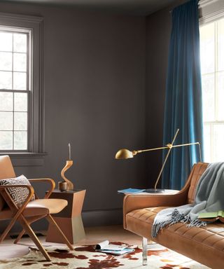 living room with dark gray walls, tan sofa and teal curtains