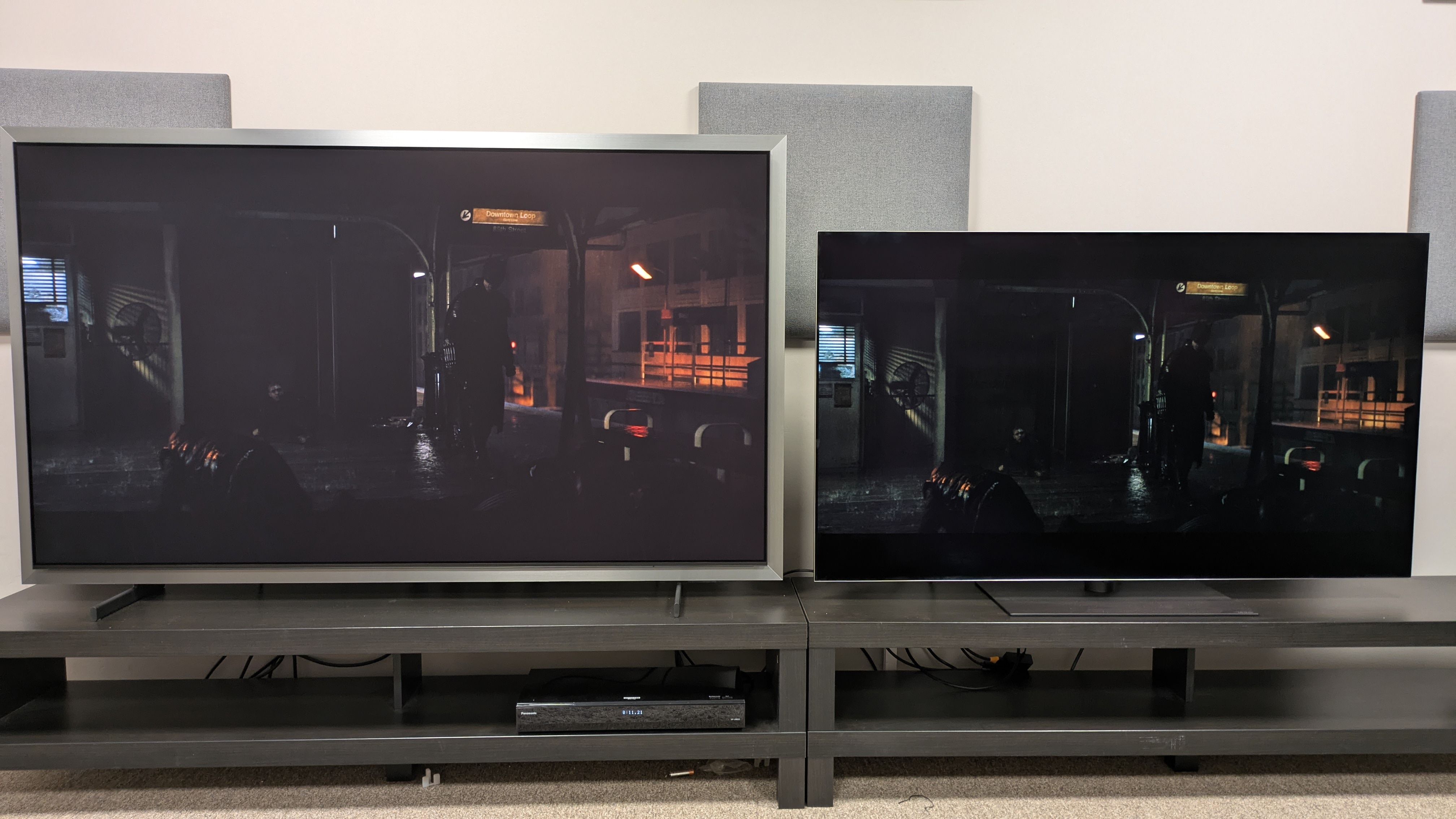 Samsung S99H (left) vs LG G6 (right) showing Batman standing in a subway platform with both TVs set to Filmmaker Mode. The S99H' screen is much dimmer resulting in a loss of detail