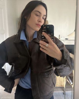 Alexa Chung wears a blue shirt with a brown leather jacket.