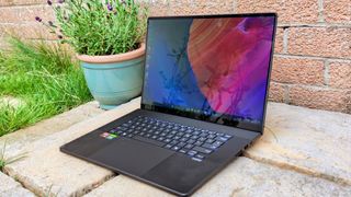 A black ASUS ProArt P16 laptop sitting on stone paving