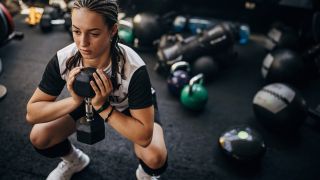 Woman performs goblet squat with dumbbell