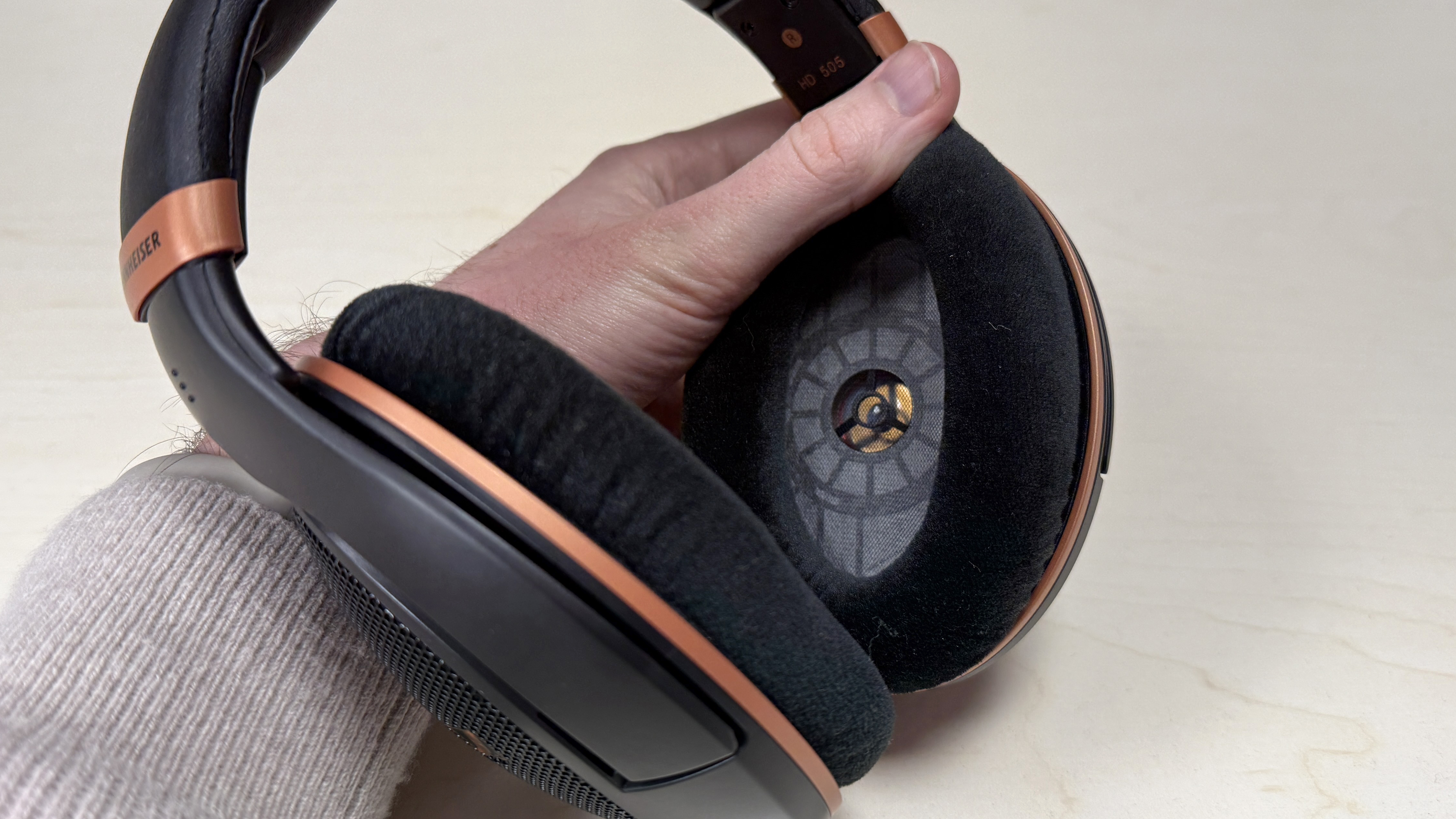 Sennheiser HD 505 headphones held in a man's hand showing the transducer