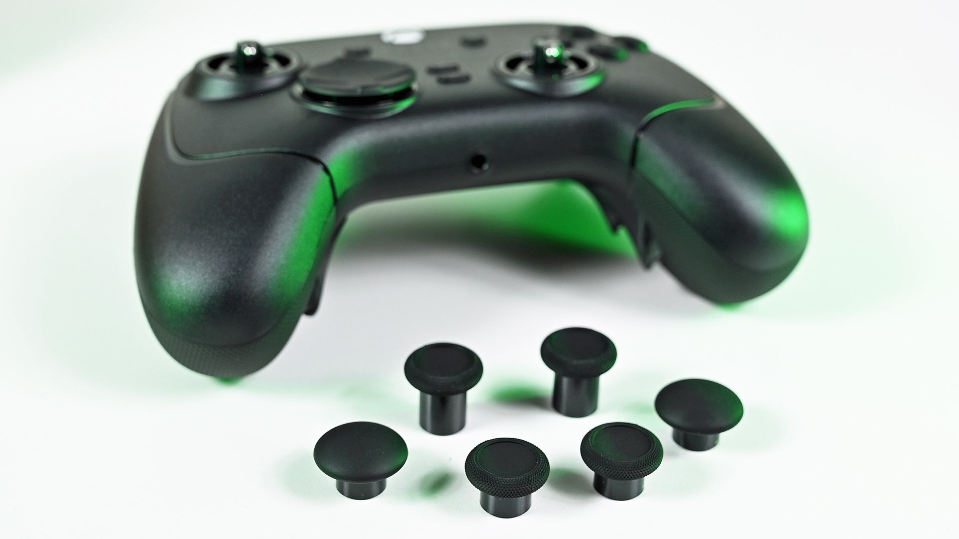 Front view of the controller with bare analog stick shafts, displayed alongside six interchangeable replacement thumbstick caps.