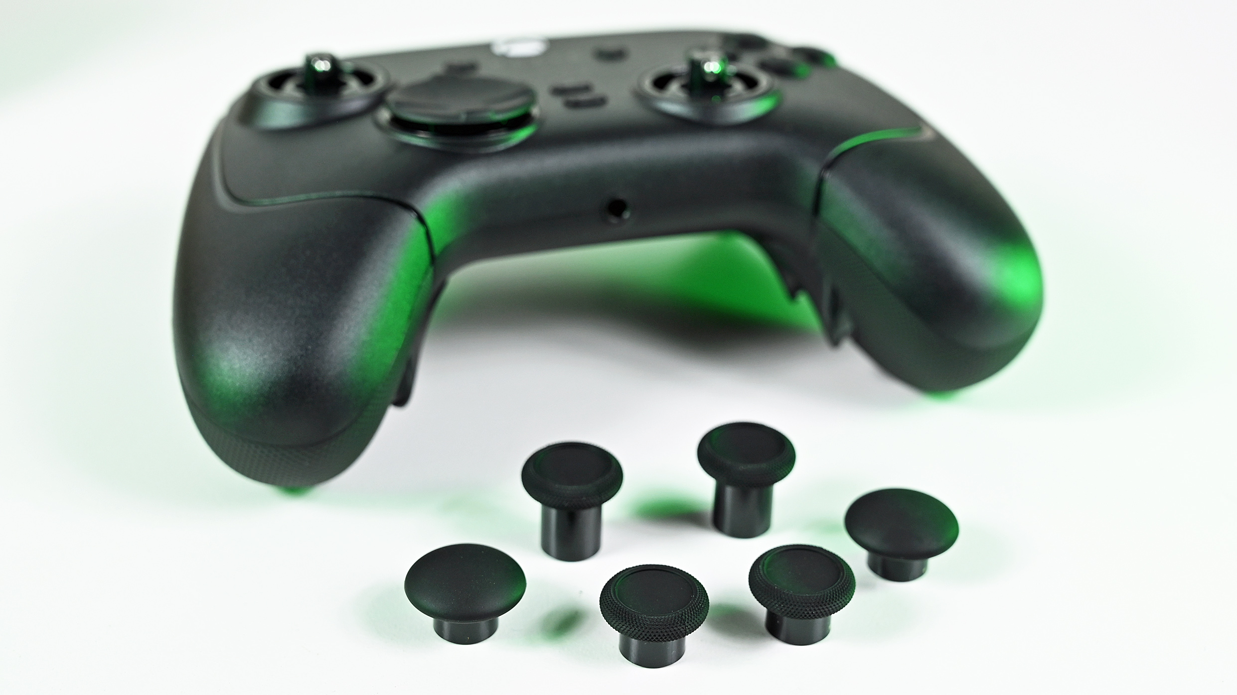 Front view of the controller with bare analog stick shafts, displayed alongside six interchangeable replacement thumbstick caps.