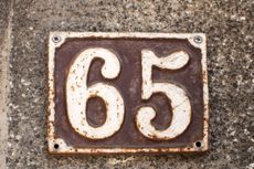metal sign with the number 65 on a stone wall