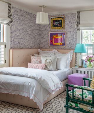 A teenager bedroom idea with lavender and white patterned wallpaper, and blush upholstered corner headboard