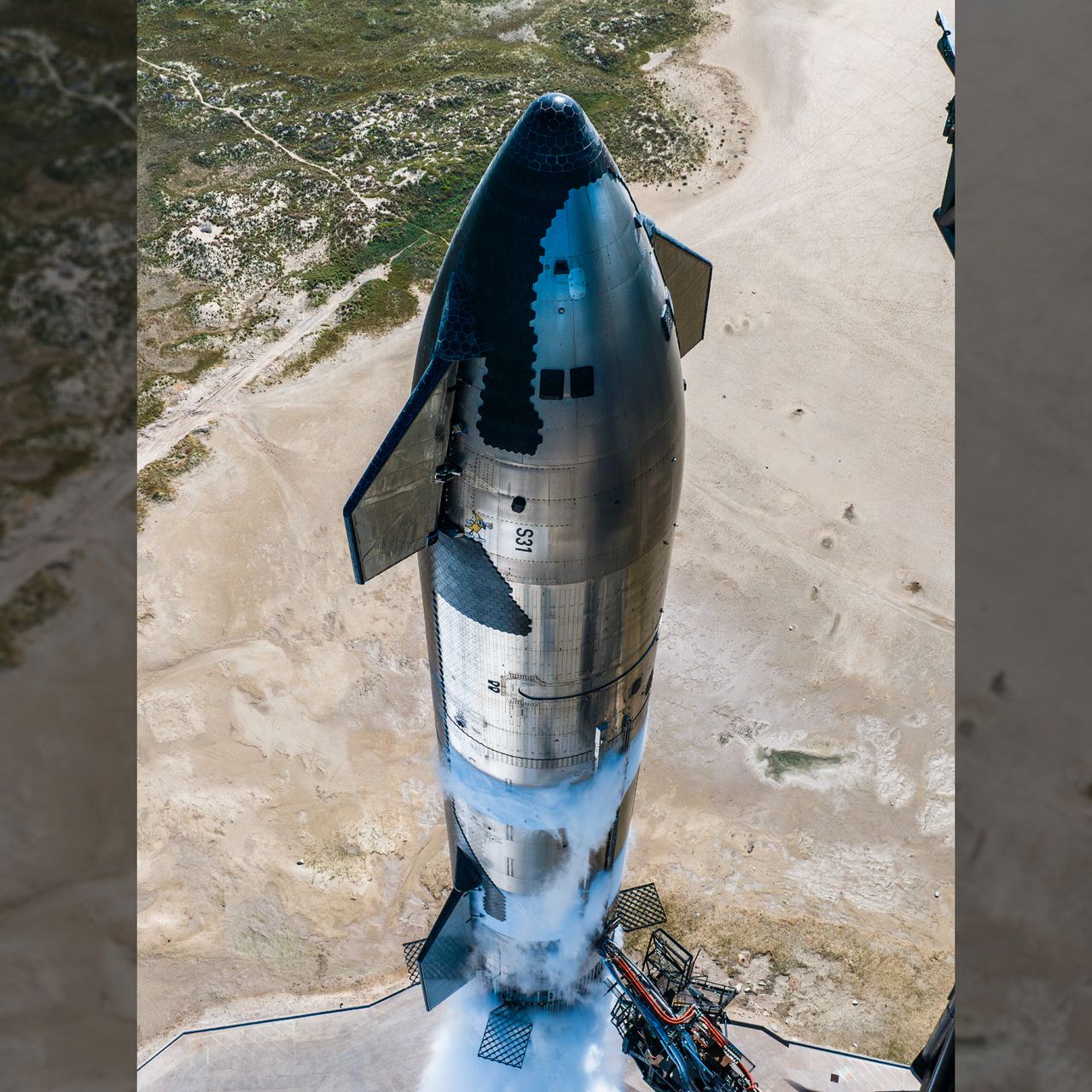 A tall chrome rocket stands next to a black tower, frosted in sections as sections are frosted white from super chilled fuel inside.