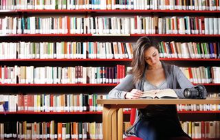 Person reading, surrounded by books