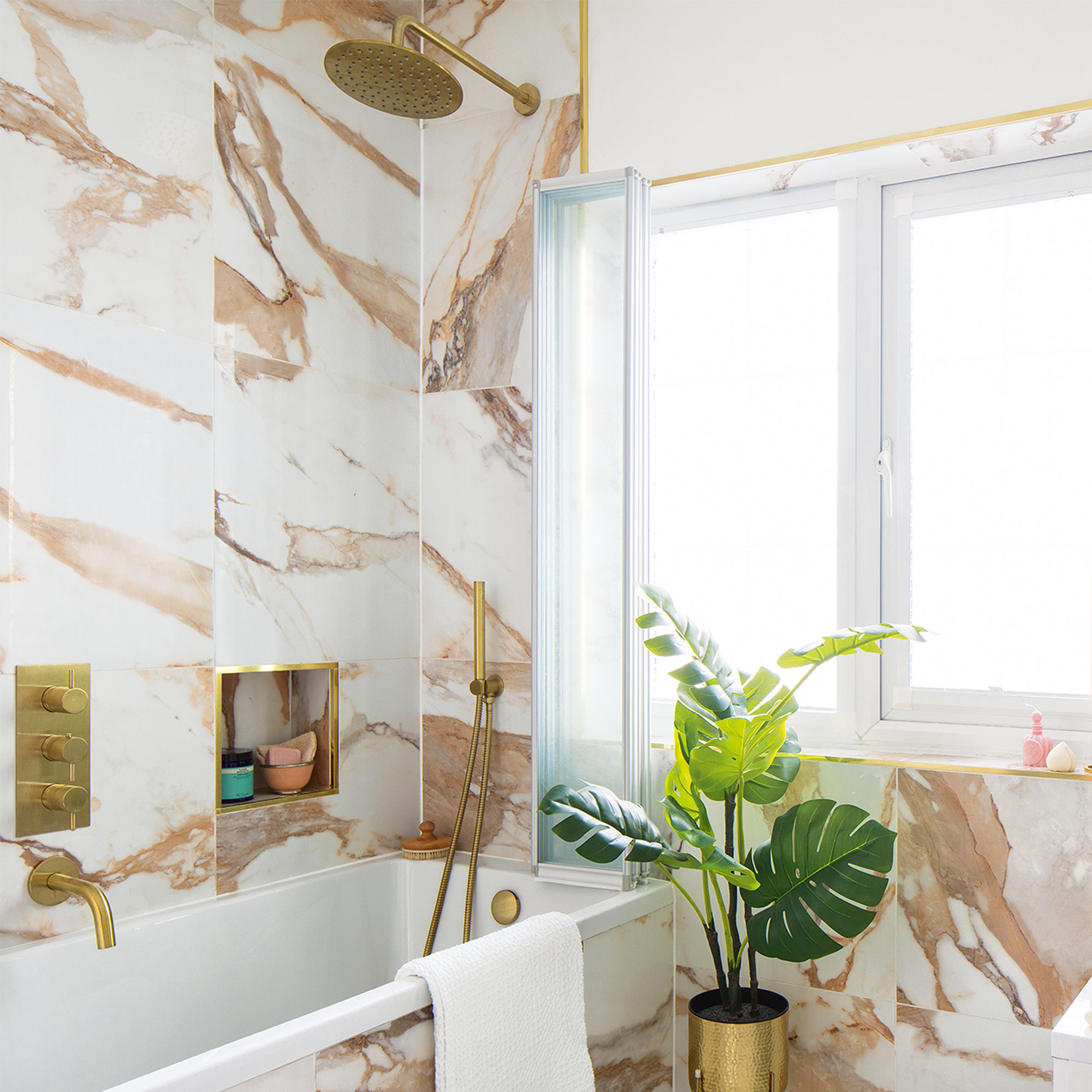marble and white bathroom with bath and gold shower
