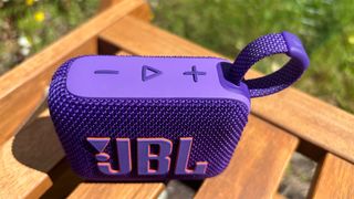 JBL Go 4 Bluetooth speaker top down view on wooden bench showing controls