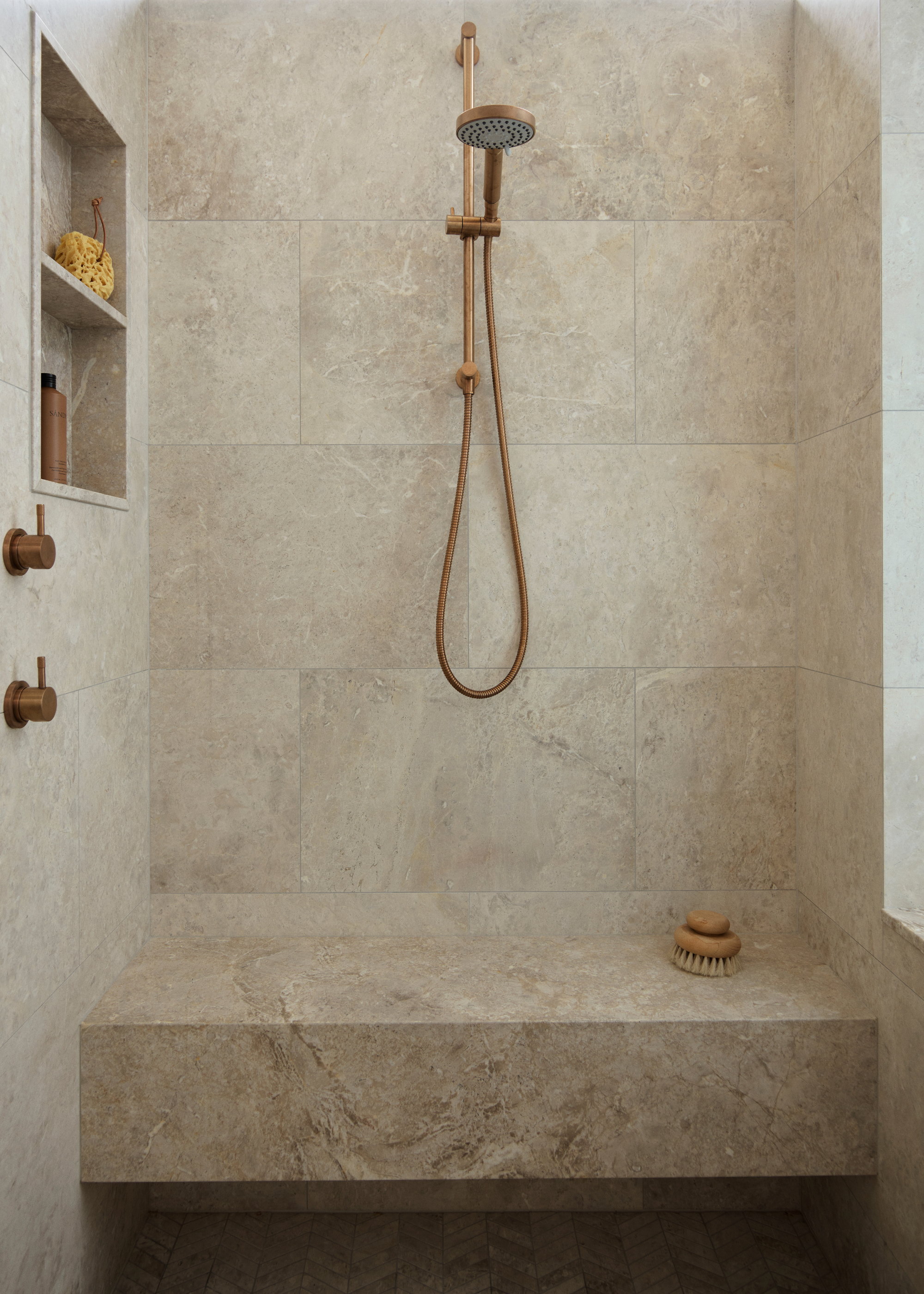 A shower with a bench and in-built shelves