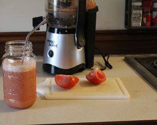 A freshly-prepared vegetable juice made using the Magic Bullet Mini Juicer served in glass jam jar drinkware with straw