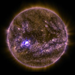 NASA's Solar Dynamics Observatory captured an image of an X2.2 solar flare on March 11, 2015, seen as a bright flash of light on the left side of the sun. Earth is shown for scale.