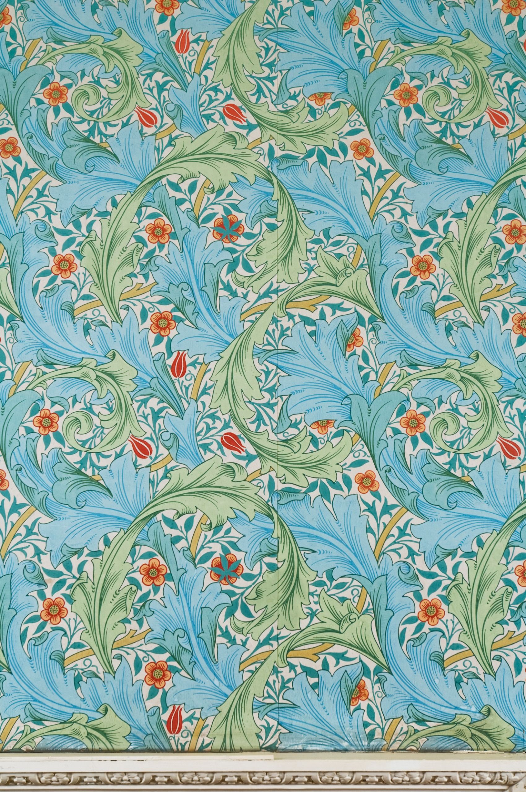 A close-up of blue, green and orange, leaf-motif wallpaper