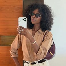 A woman taking a mirror selfie with dark brown, curly hair