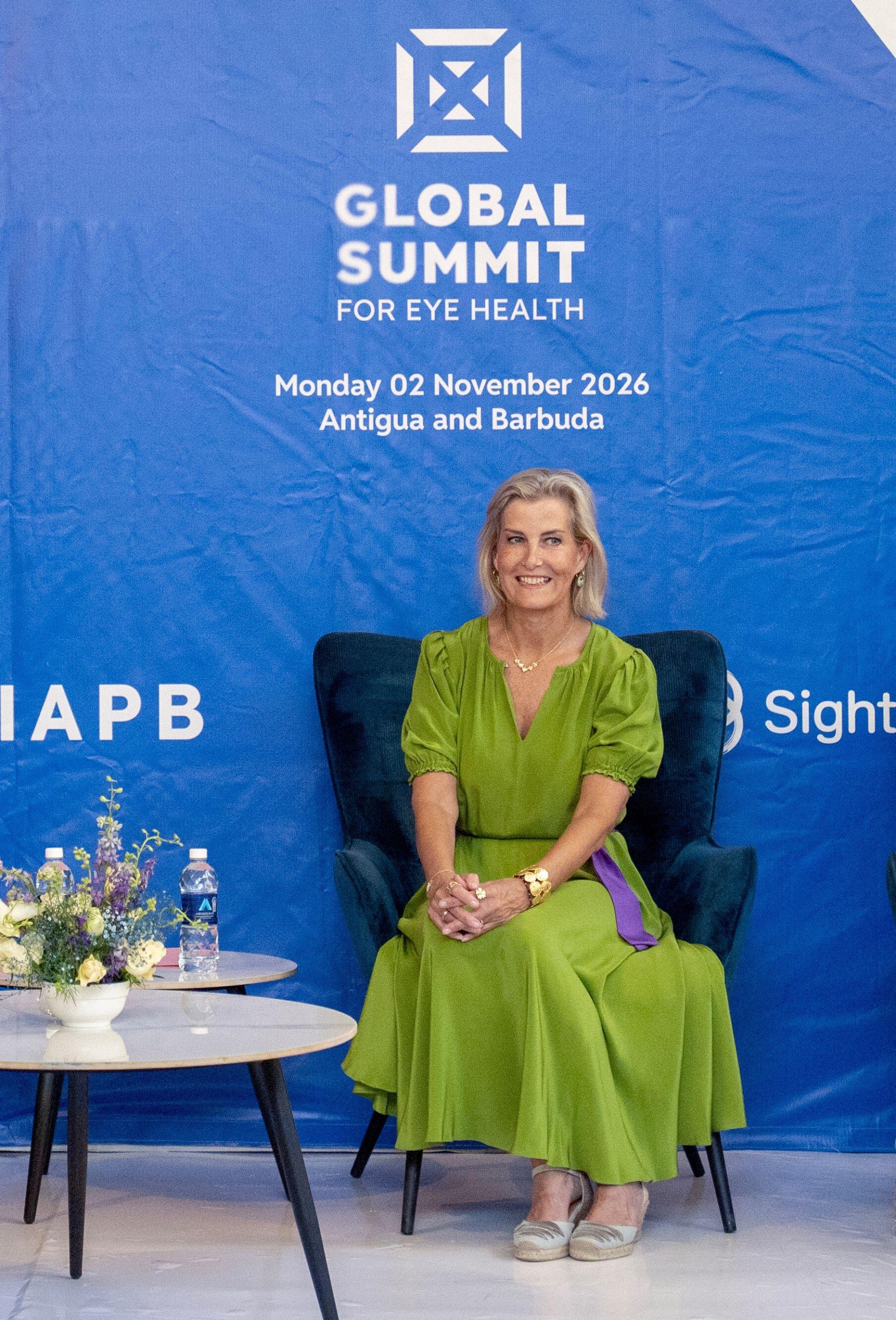 Duchess Sophie wearing a green dress sitting in a chair in front of a blue backdrop